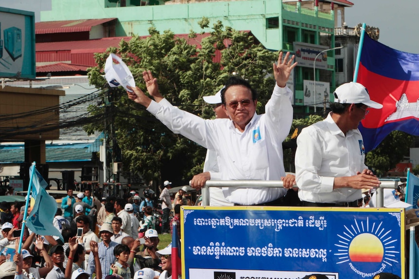 Cambodian Opposition party president Kem Sokha puts his arms in the air as he greets his supporters from a truck.