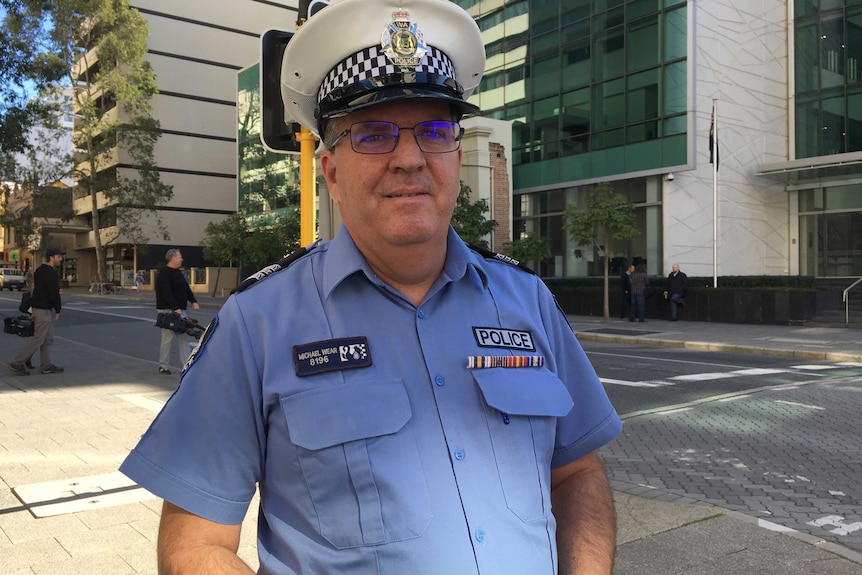 A mid shot of WA Water Police Sergeant Michael Wear standing on a Perth street in his blue uniform and cap.