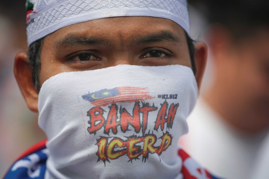 A protester covering his face takes part in a rally
