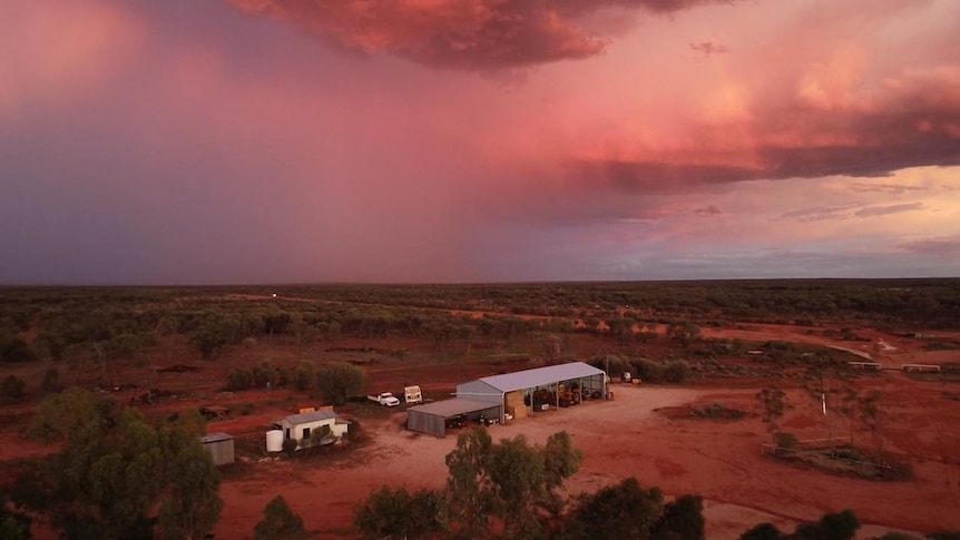 A red, cloudy sky over a property.