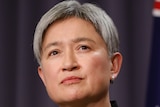 Penny Wong speaks with an Australian flag behind her