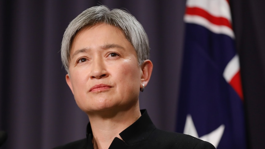 Penny Wong speaks with an Australian flag behind her