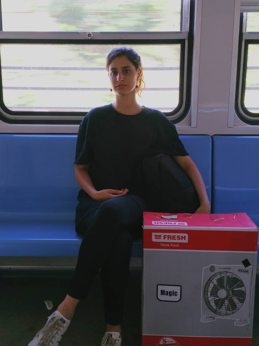 Lamisse Hamouda sits on a train with a fan.