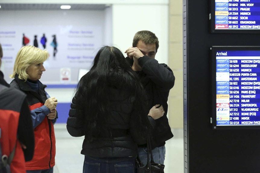 A man breaks down next to Russian Emergencies Ministry members