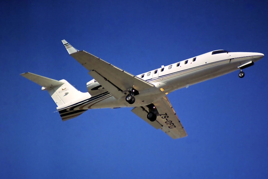 A white learjet in the sky.