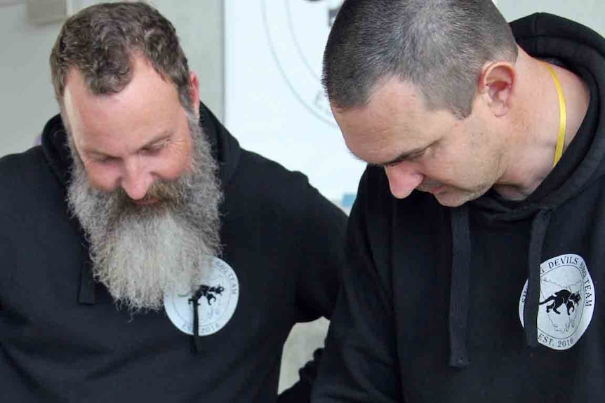 Paul Omay (l) and Justin Mayo from the Smoking Devils bbq team check the done-ness of their meat.