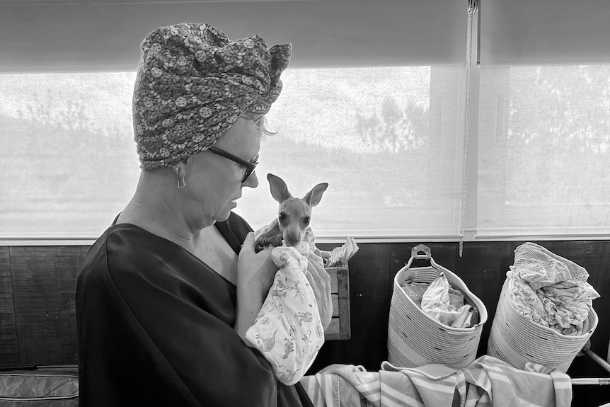 A woman holds a joey. 