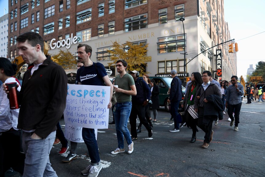 Dozens of Google employees walk in the streets holding signs.