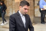 a man in a business suit walks outside a court building
