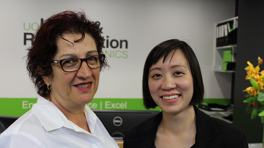 Close up of two women standing in front of an office space at the University of Queensland.
