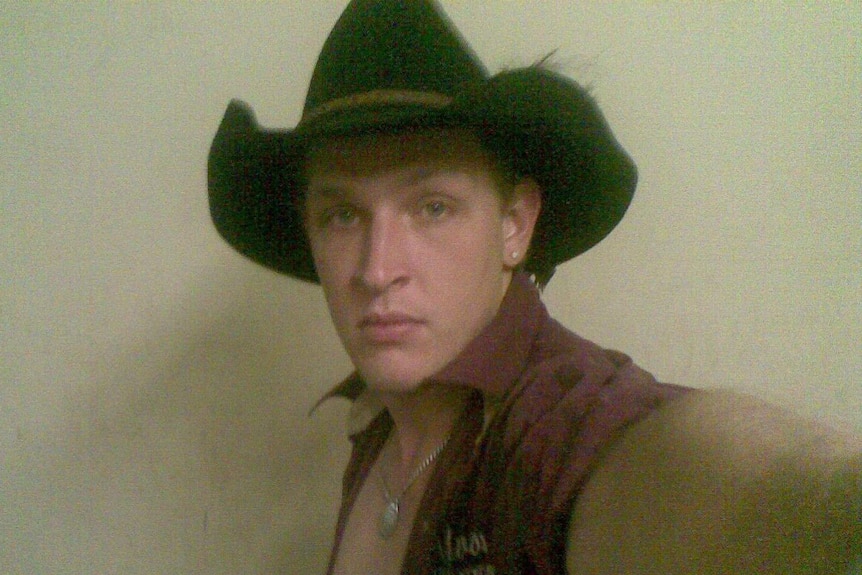 A man poses in a cowboy hat