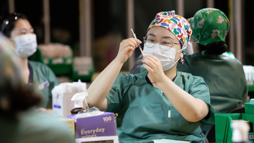 A nurse pulls up a syringe of COVID-19 vaccine.