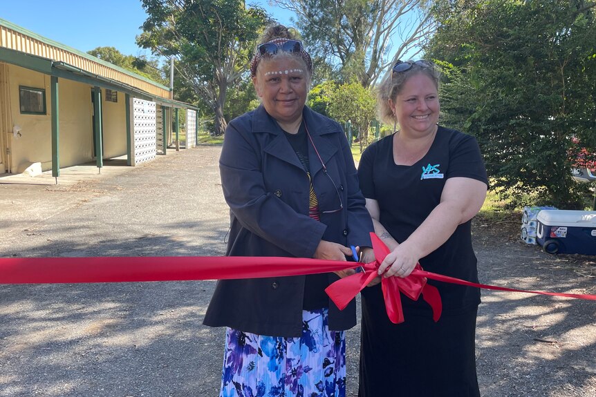 two women cut a ribbon in front of cabins 