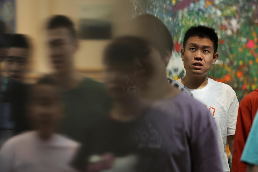Mr Zu is in focus standing while other people move in a blur around him. 