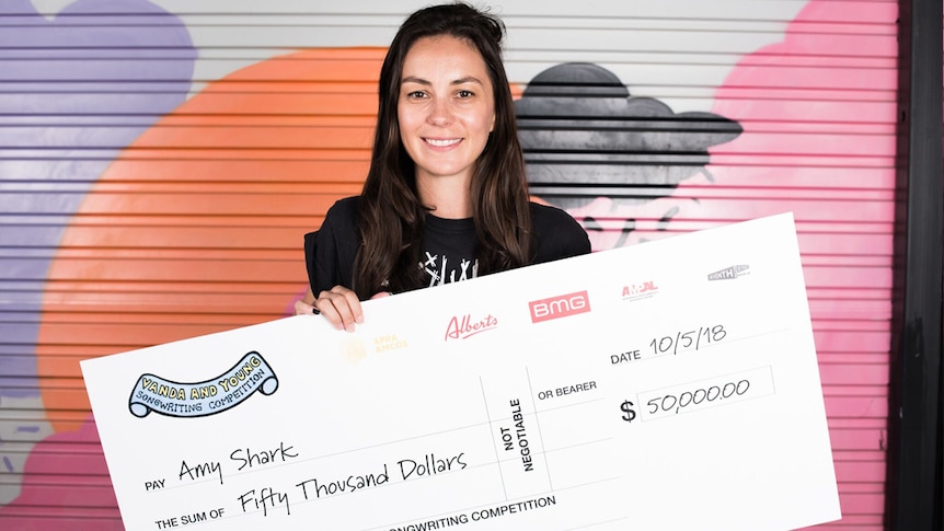 Amy Shark holding a $50,000 cheque as the 2018 Vanda and Young Songwriting Competition winner