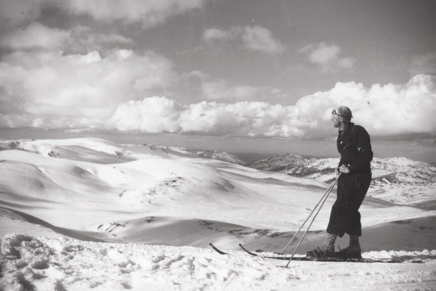 A man on skis looking over a mountain range in black and white