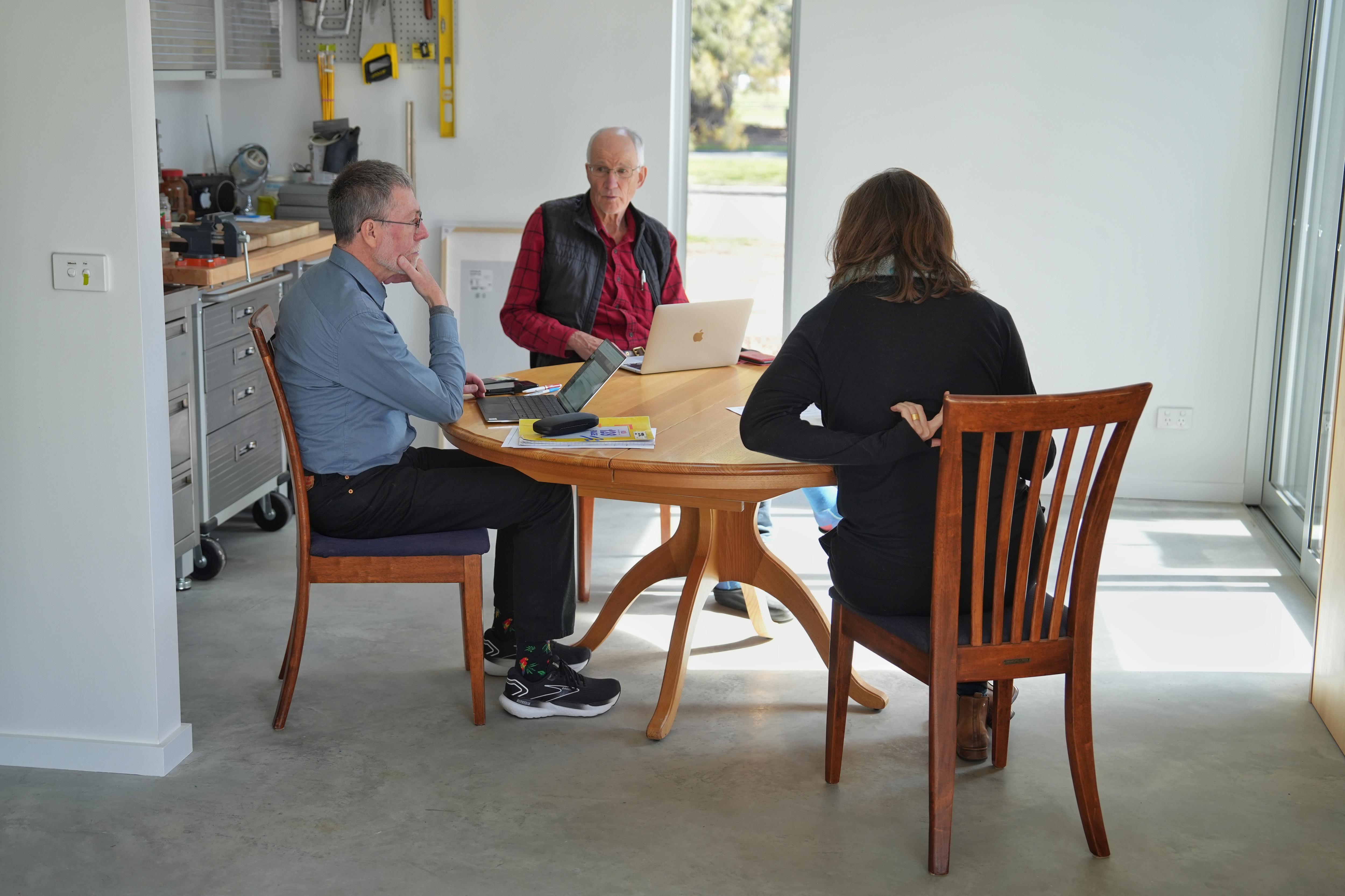 Three people sit around a kitchen table.