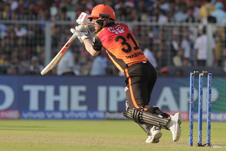 David Warner pushes his bat away from his body, leaning forwards whilst playing a shot