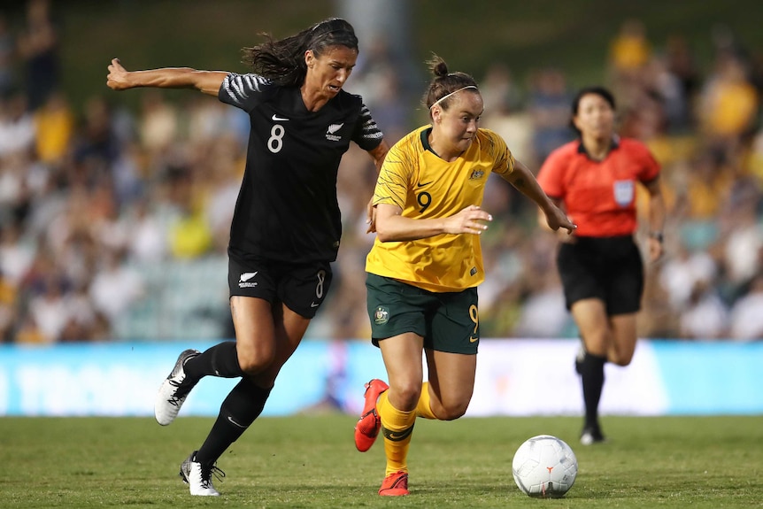 Caitlin Foord and Abby Erceg run side by side with a ball at their feet