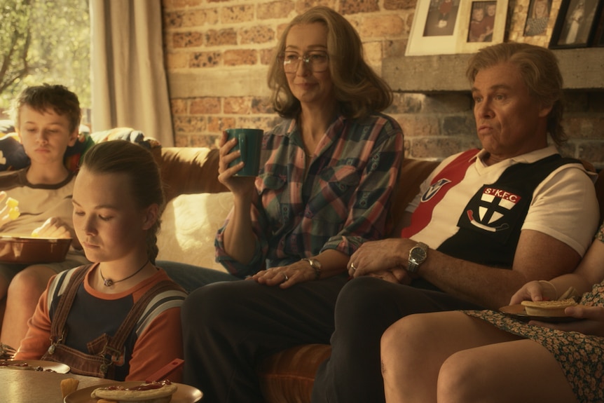 Mother, father and three children in lounge room watching TV