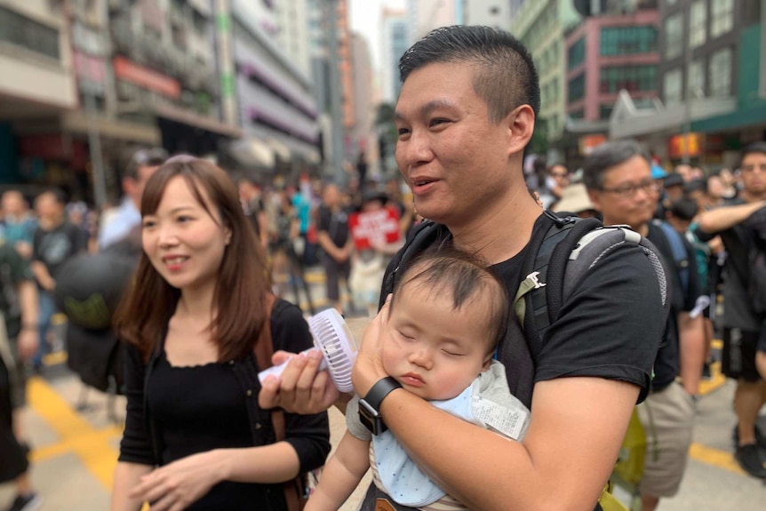 A mother, father and baby attend a protest on the streets of Hong Kong on 16 June 2019.