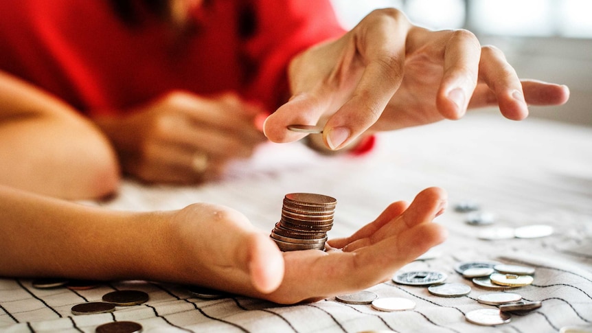 A woman counts out money into another woman's hands.