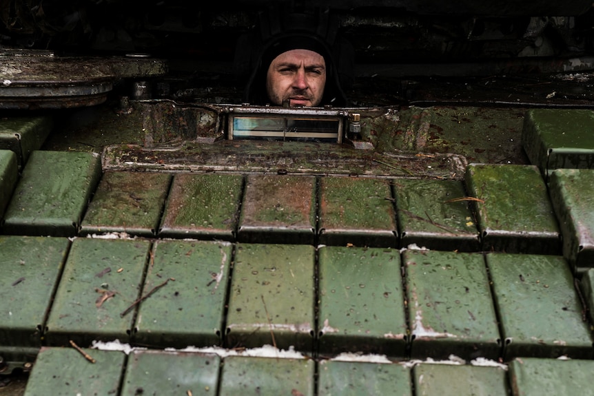 A Ukrainian serviceman looks on from inside a tank.