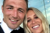 A close up selfie of a man in a suit with a smiling blond woman.