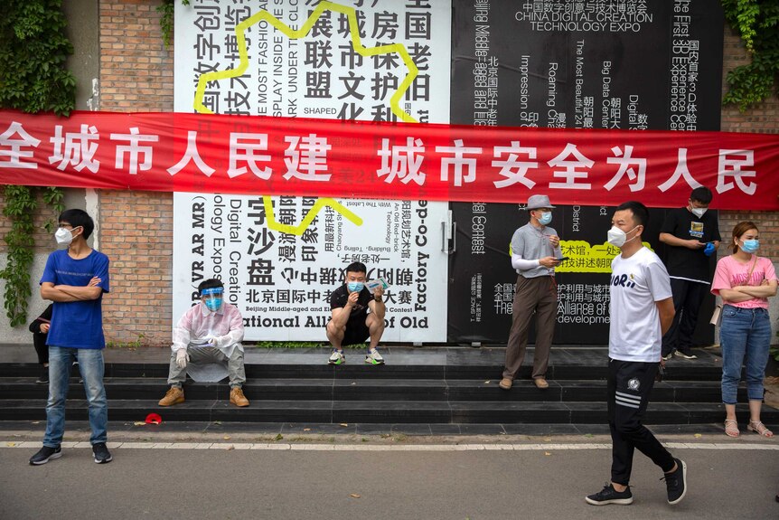 Люди ждут у полигона для тестирования на COVID-19 после того, как им приказали пройти тестирование после вспышки в Пекине.