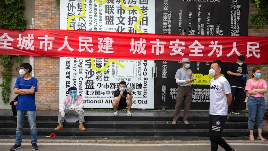 People wait outside a COVID-19 testing site after being ordered to be tested, following the Beijing outbreak.