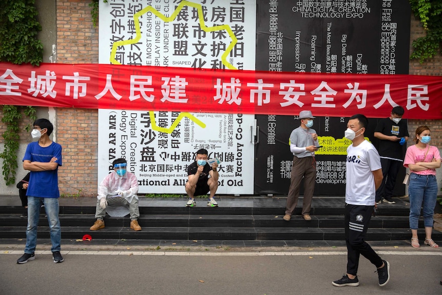 People wait outside a COVID-19 testing site after being ordered to be tested, following the Beijing outbreak.