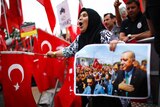 A woman yells while holding a picture of Turkish President Tayyip Erdogan and a Turkish flag.