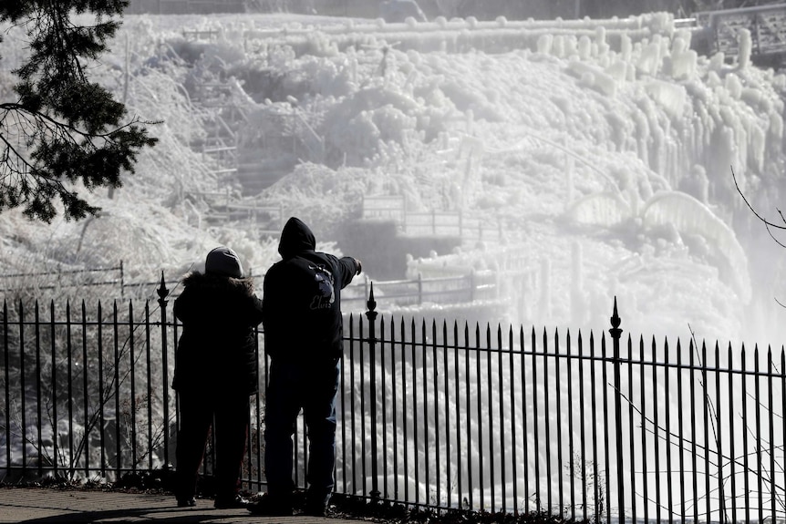 Ice is seen on the side of the Great Falls National Historic Park as a couple takes in the sights during a frigid winter day.