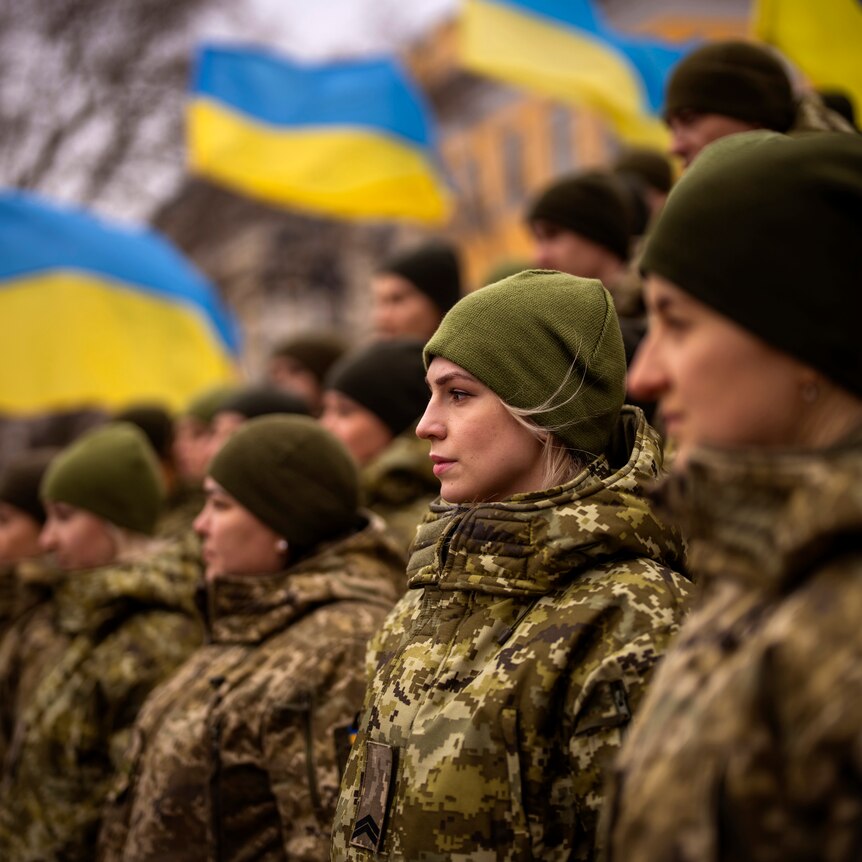 Ukrainian Army soldiers pose for a photo in front of national flags