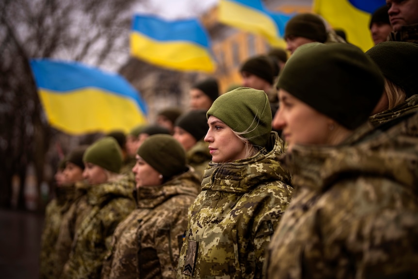 Ukrainian Army soldiers pose for a photo in front of national flags