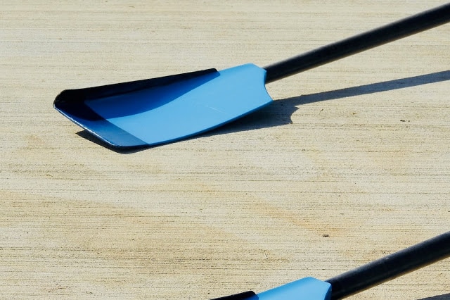 A picture of the blade of an oar, coloured blue, with a thin, black attachment on the top
