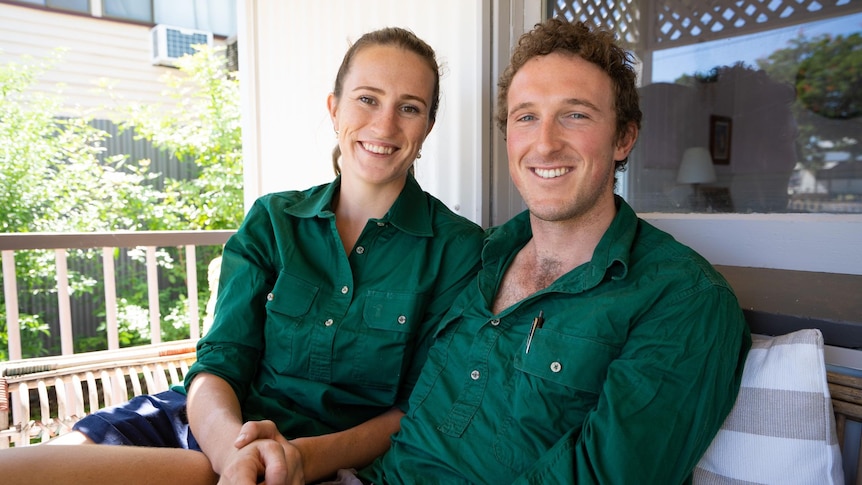 Woman and man in green shirts staring at camera