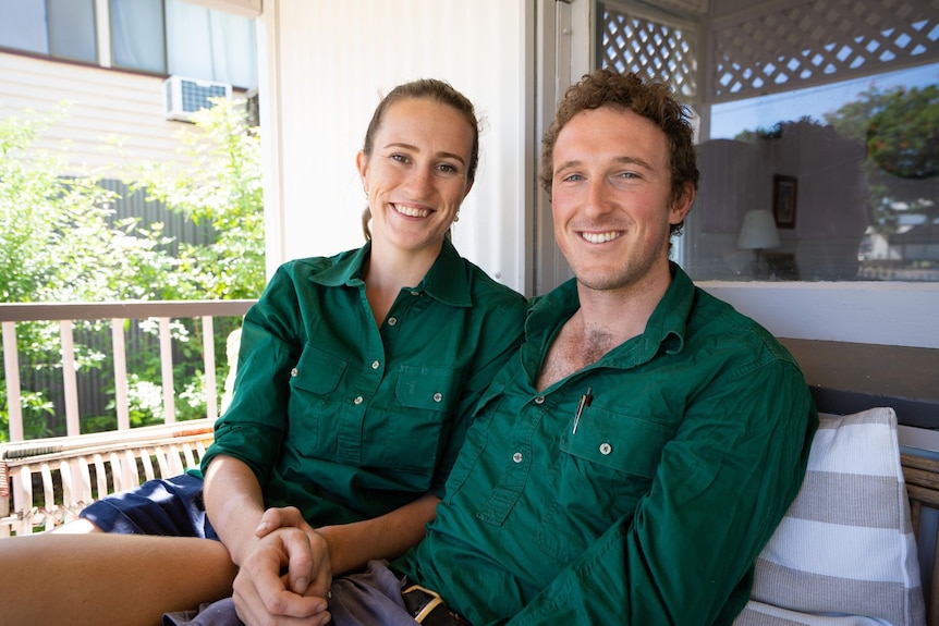 Woman and man in green shirts staring at camera