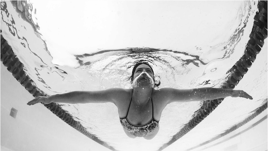 An underwater black and  photograph of a woman swimming
