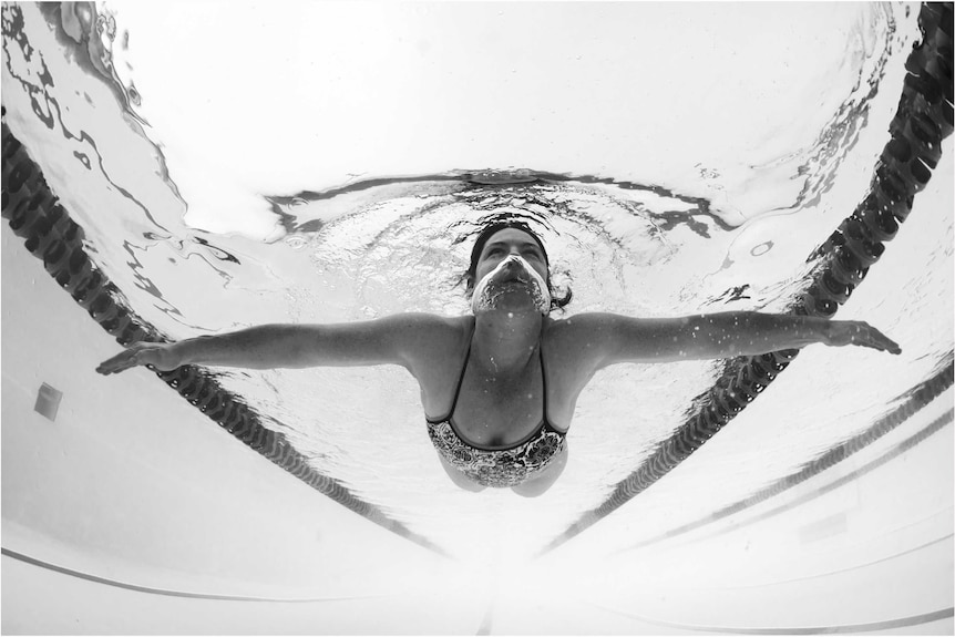 An underwater black and  photograph of a woman swimming