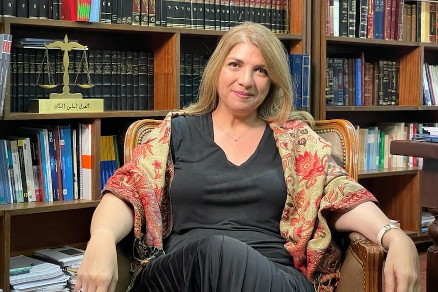 A woman sitting in front of a book case.