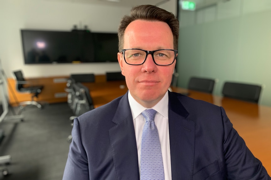 A man wearing a suit, tie and glasses.