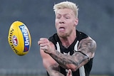 A Collingwood AFL player handballs with his left hand during a night match against Richmond at the MCG in Melbourne.