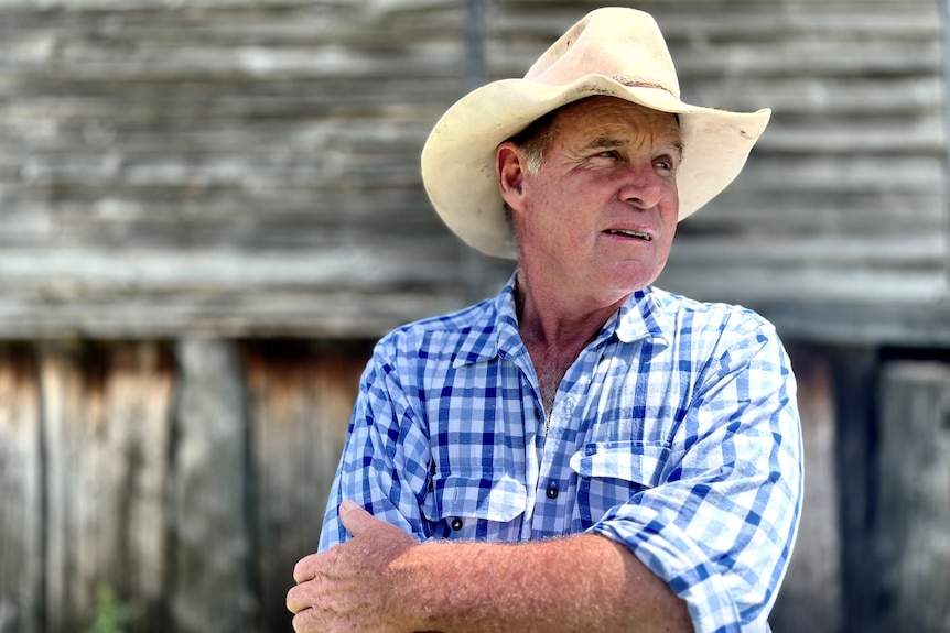 Farmer Bill Mott stands outside with arms folded and hat on.