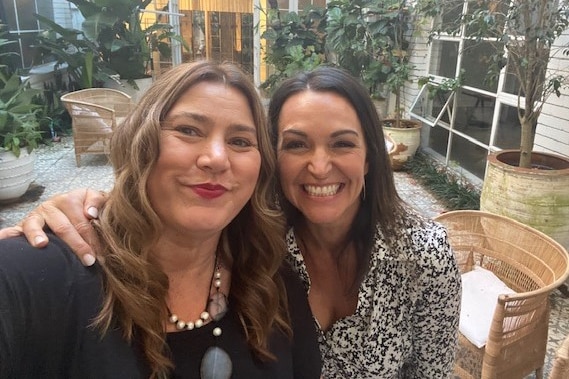Two women smile at the camera as they take a selfie.