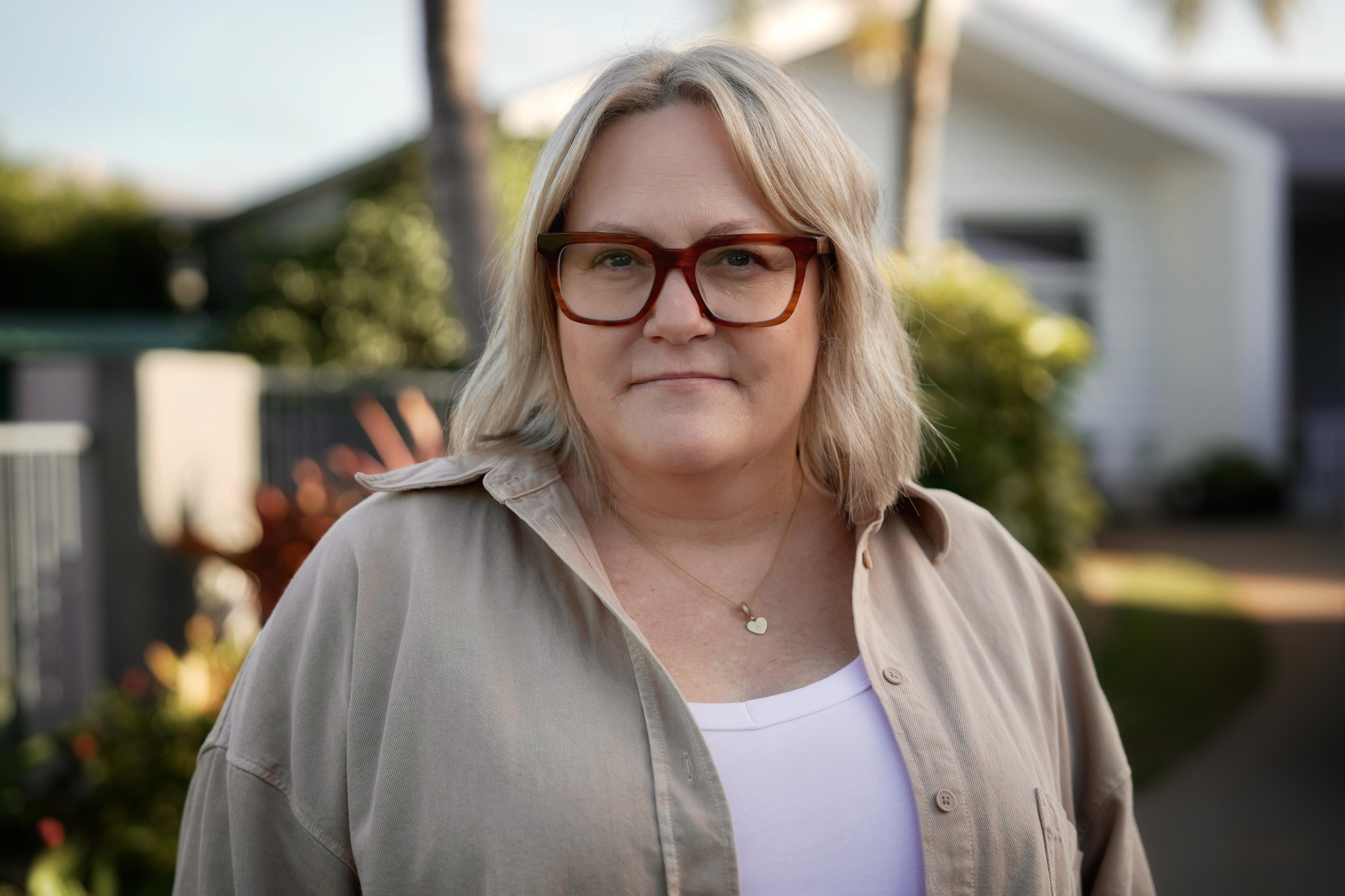 A woman with blond hair and red glasses on a suburban street