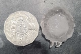 A 50 cent piece sits next to a piece of hail that's around the same size.