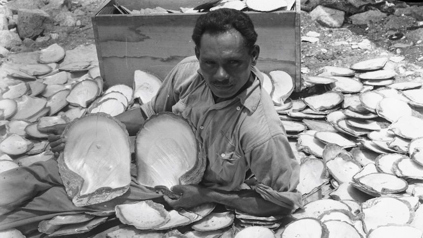 A man sitting on ground surrounded by pearl shells