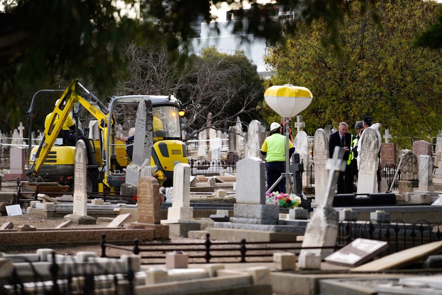 An excavation crew stands amongst gravesites