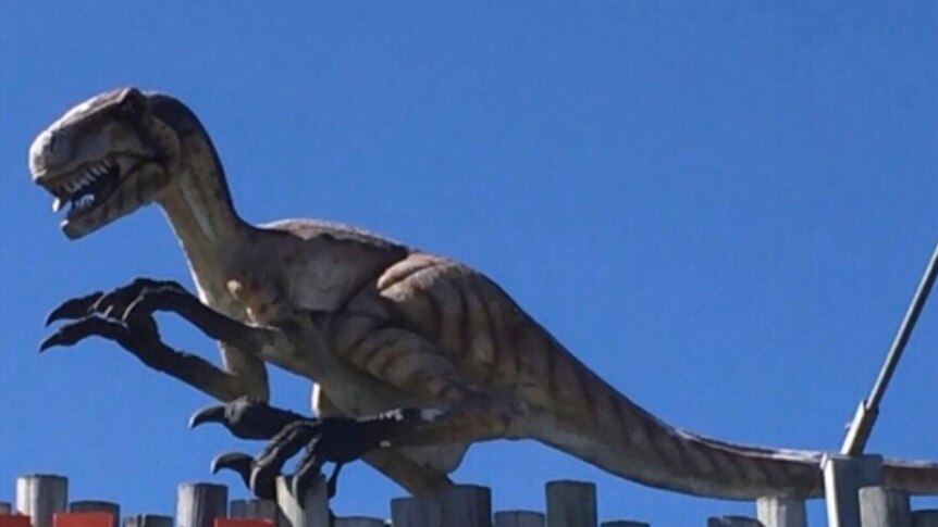 Dinosaur on top of sign.